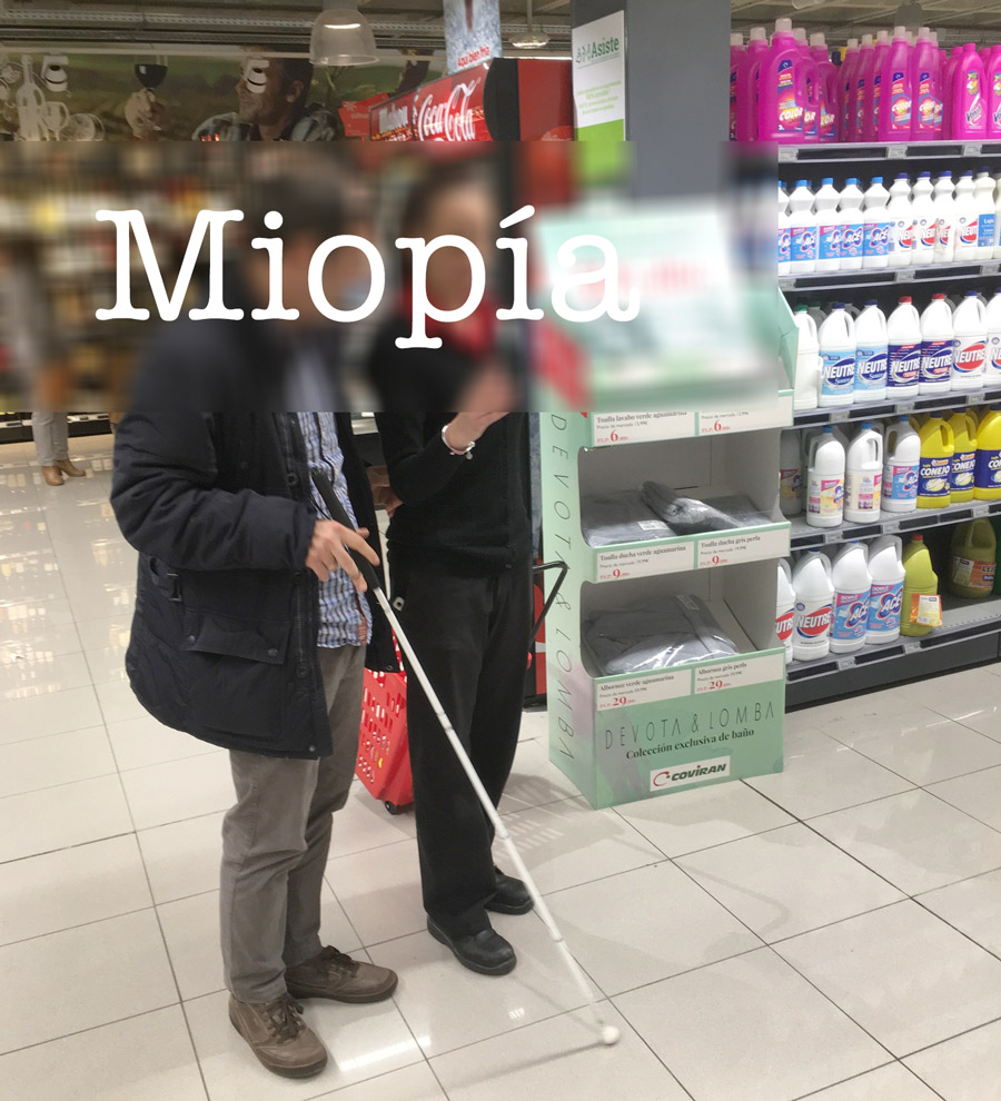 Un hombre con discapacidad visual en un supermercado acompañado por una asistente. Sus caras se ven desenfocadas por un recuadro que sirve de fondo para la palabra miopía